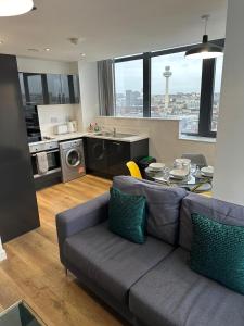 a living room with a couch and a table and a kitchen at Two Bedroom City View Apartment Liverpool in Liverpool