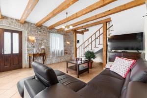 a living room with a leather couch and a flat screen tv at Holiday House with Private Pool Villa Ladybug in Milotski Breg