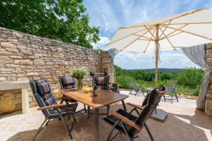 a wooden table and chairs with an umbrella at Holiday House with Private Pool Villa Ladybug in Milotski Breg