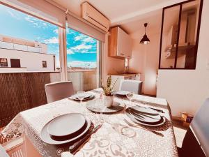 a dining room with a table and chairs and a window at T3 Paisible très proche plage climatisation et WIFI - 52 in Canet-en-Roussillon
