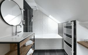 ein Badezimmer mit Waschbecken, Badewanne und Spiegel in der Unterkunft Logis Hôtel Etchemaïté in Larrau