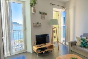 a living room with a tv and a view of the ocean at Les Sablettes in Menton