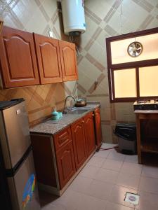 Una cocina con armarios de madera y un fregadero y una ventana. en New mohastel, en Mascate