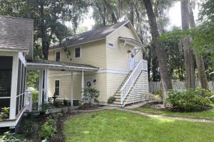 a woman standing on the stairs of a yellow house at Hickory Trace Carriage Studio in Bluffton