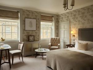 a bedroom with a bed and chairs and windows at The Queensberry Hotel in Bath