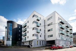科克Steelworks at Copley Court的白色的建筑,有汽车停在停车场