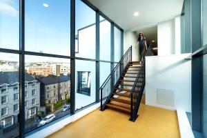 科克Steelworks at Copley Court的一名女子走下带有大窗户的建筑物的楼梯
