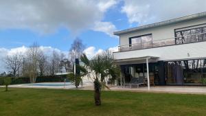 a house with a palm tree in the yard at Maison Mélusine ossature bois forêt de Brocéliande in Néant-sur-Yvel