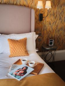 a tray with two cups and a book on a bed at The Queensberry Hotel in Bath