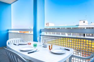 een witte tafel met stoelen en borden op een balkon bij Condominio Athena in Bibione