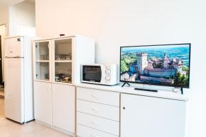 een wit entertainmentcentrum met een tv en een magnetron bij Condominio Athena in Bibione