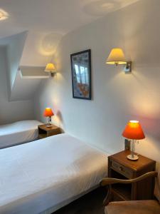 a bedroom with two beds and two lamps on tables at Hôtel Restaurant l'Annexe in Saint-Valéry-en-Caux
