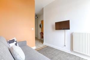 a living room with a couch and a flat screen tv at Mykeypers - Studio Cozy 2P - Malakoff 11 in Malakoff +9 photos