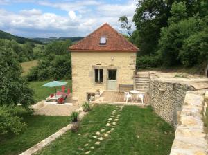 ein kleines Steinhaus mit einem Tisch und einer Terrasse in der Unterkunft Les Tanneries in Flavigny-sur-Ozerain