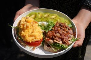 a person holding a bowl of food with a sandwich at Yangshuo Hillside Homestay in Yangshuo