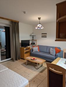 ein Wohnzimmer mit einem blauen Sofa und einem Tisch in der Unterkunft Studio mit Meerblick auf die Robbenbänke von Norderney, geschützter Südwestbalkon in Baltrum