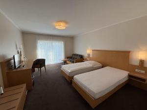 a hotel room with two beds and a television at Hotel Restaurant Brinckwirth in Ochtrup