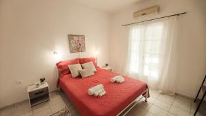 a bedroom with a red bed with two stuffed animals on it at Spiros House in Roda