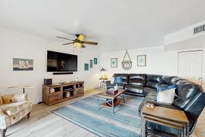 a living room with a leather couch and a flat screen tv at Reef Club 107 in Clearwater Beach