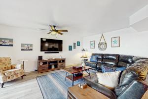 a living room with a leather couch and a flat screen tv at Reef Club 107 in Clearwater Beach +46 photos