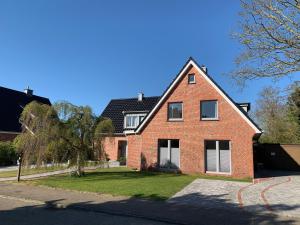 a red brick house with white windows on a street at Dünenhus Borkum in Borkum