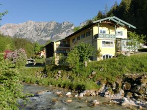 a house on a hill next to a river at Ferienwohnungen Martinsklause in Ramsau