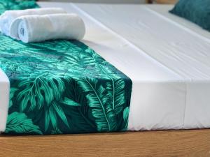 a bed with a green and white blanket and towels at Villa Océan Gravier Rodrigues in Mt Bois Noir