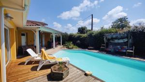 a swimming pool on a wooden deck next to a house at La Suite Soleil in Gujan-Mestras