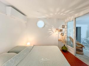 ein weißes Schlafzimmer mit einem Bett und einem Fenster in der Unterkunft La Marinièro à 350m des plages - 4 couchages - Wifi in Toulon