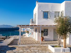 a white house on the side of the ocean at Sunset Windmills House in Mikonos