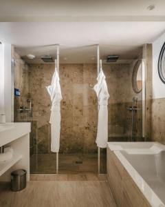 a bathroom with a shower and a tub and a sink at Hôtel Les Roches Blanches Cassis in Cassis