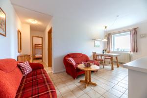 a living room with a red couch and a table at Ferienhof Bruhn "Nr 2" in Midlum
