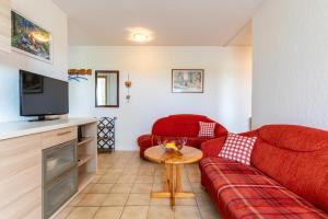 a living room with a red couch and a table at Ferienhof Bruhn "Nr 2" in Midlum
