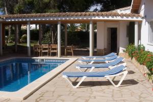 a group of lounge chairs next to a swimming pool at Villa Mediterránea in Calafat