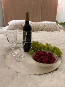a plate of grapes and a bottle of wine and a bowl of fruit at Apartament Pod Żaglami 1 in Sława