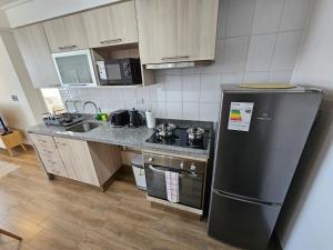 a kitchen with a black refrigerator and a sink at 2D con estacionamiento Fantastico Depto - D'Home in Concepción