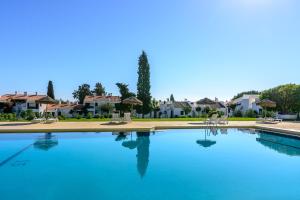 a large blue swimming pool with houses in the background at Pedras Da Rainha in Cabanas de Tavira