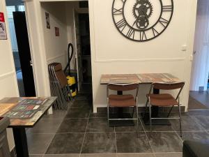 a room with two tables and a large clock on the wall at Chez Nathan appartement 2 chambres in Auxerre +9 photos