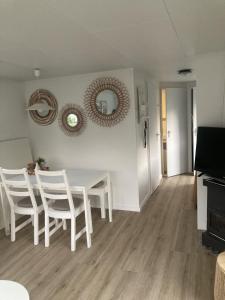 a dining room with a white table and white chairs at KD 822 - Vakantiepark Kijkduin in The Hague