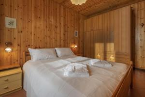a bedroom with a large white bed with wooden walls at Due gnomi in Temù