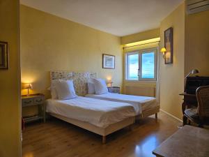 a bedroom with a bed with white sheets and a window at La Terre d'Or in Beaune