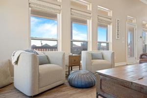 a living room with two chairs and a table and windows at Nauti By Nature home in Crystal Beach +46 photos