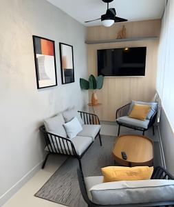 a living room with two chairs and a tv at Estúdio SPA Elegante! Jacuzzi privativa! 1407 in Sorocaba