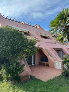 a pink house with a palm tree in front of it at Domus Strazza Porto Quadro in Santa Teresa Gallura