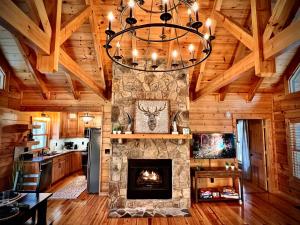 a living room with a stone fireplace and a chandelier at Mountain Hideaway - Hot Tub, Fire Pit, Close to Town in Ellijay