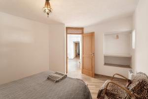 a bedroom with a bed and chairs and a hallway at Cueva la Umbría Artenara Vacacional in Artenara