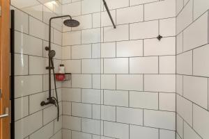 a bathroom with a shower with white tiled walls at Cueva la Umbría Artenara Vacacional in Artenara +19 photos