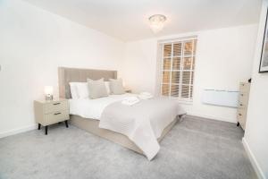 a white bedroom with a large bed and a window at The Cheltenham Suites - Fabulous 1 Bed Apartment in Cheltenham