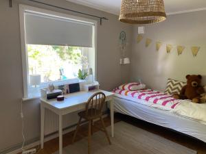 a bedroom with a bed with a desk and a window at Family-friendly house near the sea in TrÃ¤slÃ¶vslÃ¤ge
