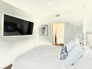 a white bedroom with a bed and a flat screen tv at Spacious and Central with a Pool View in Los Angeles +6 photos